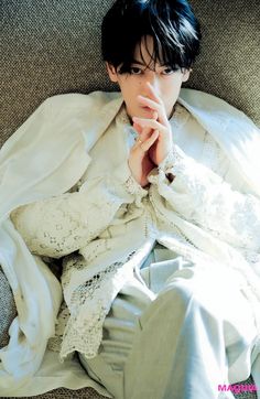 a woman laying on top of a couch under a white blanket and wearing an unbuttoned shirt