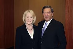 a man and woman standing next to each other in front of wood paneled walls