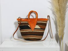 Woven Sisal Bag, African Sisal Bag, Woven Crossbody Bag, Woven Kenyan Kiondo, Boho Sling Bag, Shoulder bag, Christmas Gift for her, Mom gift This beautiful basket is made using sisal. The leaves of the sisal plant are cut down. The juice is extracted from the leaves then dried under the sun. The sisal fiber is then immersed in colored dye and left to dry. The sisal fiber is then intertwined to make the beautiful patterns. The sisal bag is durable and can compliment any outfit. Has an inner lining Dimensions: Height: 9 inches/ 23 cm Width: 9 inches/ 23 cm Strap length: 45 inches/114 cm (Adjustable) Shipping via DHL Express that take 3-5 days to be delivered. Click here to shop more bags: https://www.etsy.com/shop/ZuriWovenBaskets?ref=shop-header-name&listing_id=1480258283&section_id=4143861 Bucket Satchel With Top Carry Handle For Gift, Bucket Shaped Satchel With Top Carry Handle For Gift, Bucket Bag With Leather Handles As A Gift, Bucket Bag With Leather Top Handle As A Gift, Bucket Bag With Leather Top Handle For Gift, Brown Bucket Bag With Top Handle As Gift, Orange Top Handle Bags With Leather Handles, Rectangular Orange Bucket Bag With Adjustable Strap, Brown Bucket Bag With Top Carry Handle