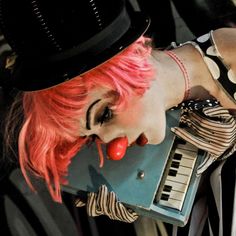 a woman with pink hair wearing a top hat and holding a keyboard in her hand