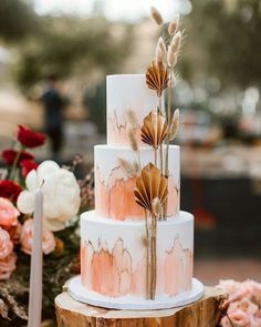 a white and pink wedding cake with flowers on top