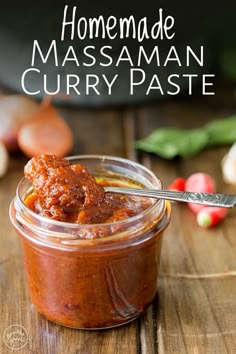 a glass jar filled with curry paste sitting on top of a wooden table