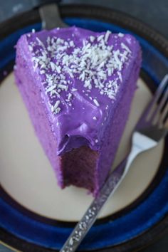 a piece of cake with purple frosting and sprinkles sits on a plate