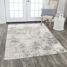 a living room area with hardwood floors and white furniture, including a large rug on the floor