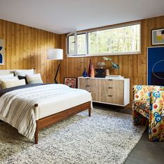 a bedroom with wood paneled walls and a white bed in the center surrounded by colorful furniture