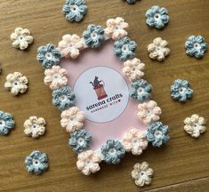 small crocheted flowers are arranged on a wooden table with a sign that says cotton crafts