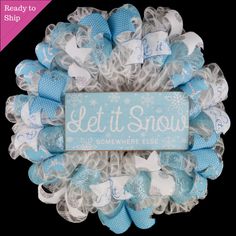 a blue and white mesh wreath with let it snow written on the front, surrounded by bows