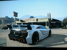 a white sports car parked in front of a gas station with mountains in the background