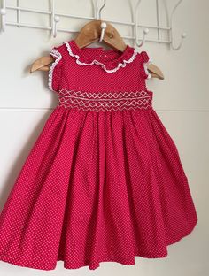 This gorgeous red handmade xmas smocked girls dress is made with a 100% cotton polka dot fabric with a beautiful hand smocked yoke in white.  Back closure with buttons and a tie back waist.  This is a beautiful baby girls dress and perfect for the upcoming festive season Size 9-6 months  Length of dress  16" Chest is 19" around. Fitted Red Smock Dress, Red Cotton Dress With Smocked Back, Red Sleeveless Smocked Dress, Fitted Red Cotton Smocked Dress, Red Fitted Cotton Smocked Dress, Cute Sleeveless Dress With Smocked Cuffs, Red Cotton Dress With Smocked Bodice, Cute Red Smock Dress, Red Cotton Smocked Dress