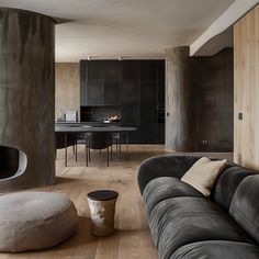 a living room filled with furniture next to a dining table and round ottoman in front of a fireplace