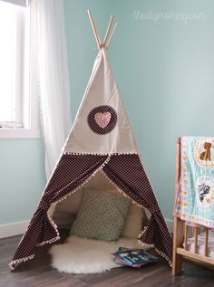 a teepee tent sitting on top of a wooden floor next to a baby crib