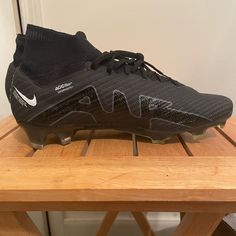 a pair of black nike soccer cleats sitting on a wooden table next to a white wall