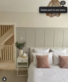 a bed with white sheets and pink pillows in a bedroom next to a stair case