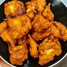 fried food in a black bowl being held by someone's hand with a toothpick