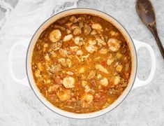 a large pot filled with food on top of a table next to a wooden spoon