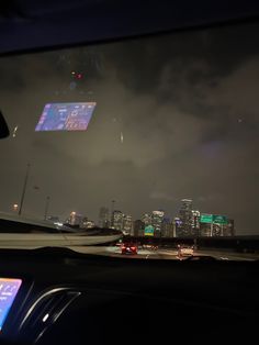 the city lights shine brightly in the distance as seen from inside a car at night