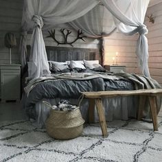 a bed with white drapes over it and a wooden bench in front of it