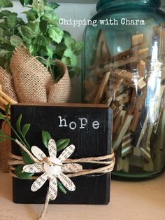 a wooden block with the word hope tied to it and some plants in front of it