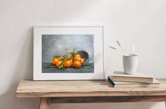 a painting of oranges on a table next to a coffee cup and two books