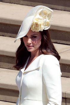 a woman in a white dress and hat walking down steps with her hand on her hip