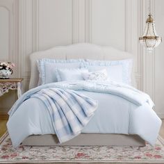 a bed with blue and white comforters in a room next to a chandelier