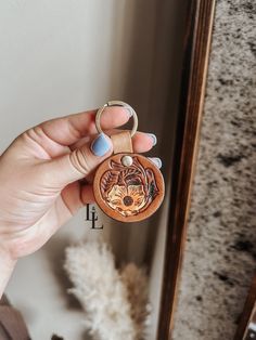 a hand holding a wooden keychain with an animal on it