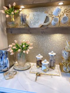 a kitchen counter topped with lots of cups and vases next to a coffee maker