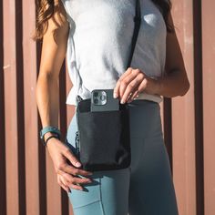 a woman holding a camera in her right hand while wearing leggings and a tank top