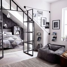 an attic bedroom with black and white decor on the walls, carpeted flooring and gray bedding