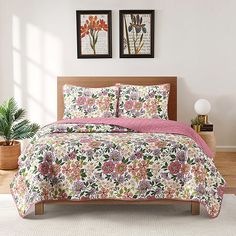 a bed in a room with two pictures on the wall and one has a pink flowered comforter