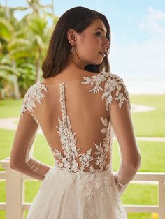 the back of a woman's wedding dress with white lace and flowers on it