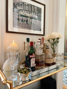 a bar cart with liquor bottles and glasses on it in front of a framed photograph