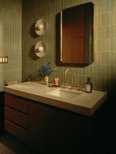 a bathroom sink sitting under a mirror next to a wall mounted soap dispenser