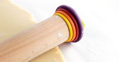 a close up of a rolling dough on a white surface with a wooden roller attached to it