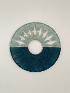 a blue and white circular object hanging on the wall in front of a white wall