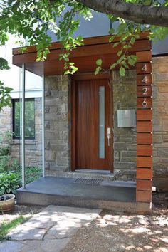 a wooden door sitting in the side of a stone building next to a lush green tree