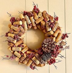 a wreath made out of wine corks, pine cones and berries on a wall