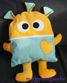 a yellow stuffed animal with big eyes and a heart on it's chest