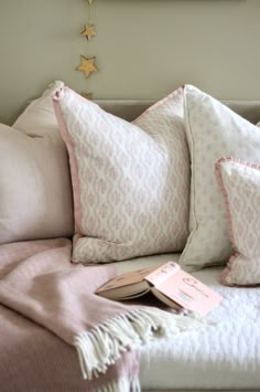 a bed with pink and white pillows on top of it next to a star decoration