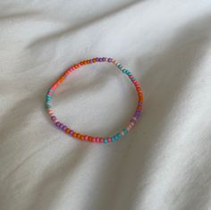 a colorful beaded bracelet sitting on top of a white sheet