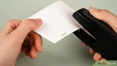 two hands holding a piece of paper and a stapler