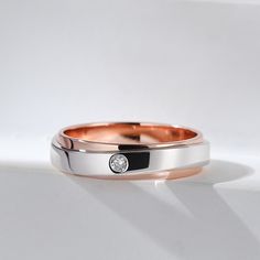 two wedding bands with a diamond in the center on a white surface, one is pink gold and the other is silver