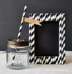 a mason jar with a straw in it next to a black and white striped frame