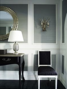 a black table with a lamp and mirror on it in a room that has white walls