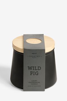 a black candle with a wooden lid and label on the top that says wild fig