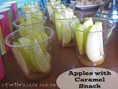 apples with caramel snack mix in plastic cups on a wooden table next to other food items