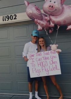 a man and woman standing next to each other holding pink balloons with pigs on them