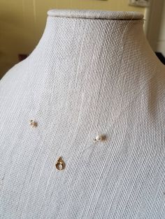 a white mannequin with two gold earrings on it