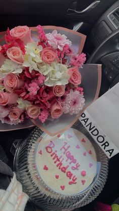 a bouquet of pink roses sitting on top of a table next to a birthday cake