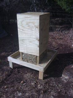 a beehive sitting on top of a wooden platform in the dirt next to trees